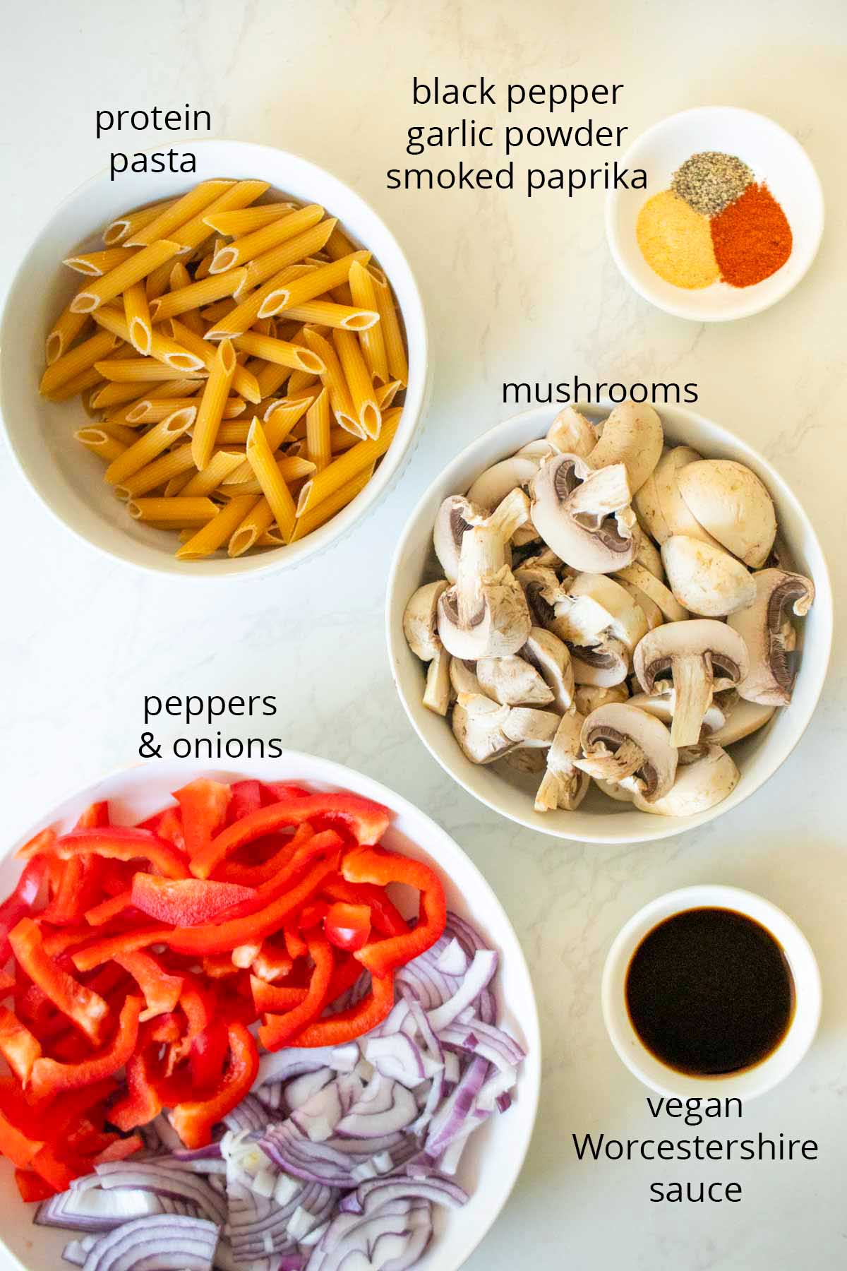 vegan Philly cheesesteak pasta ingredients in bowls on a white table