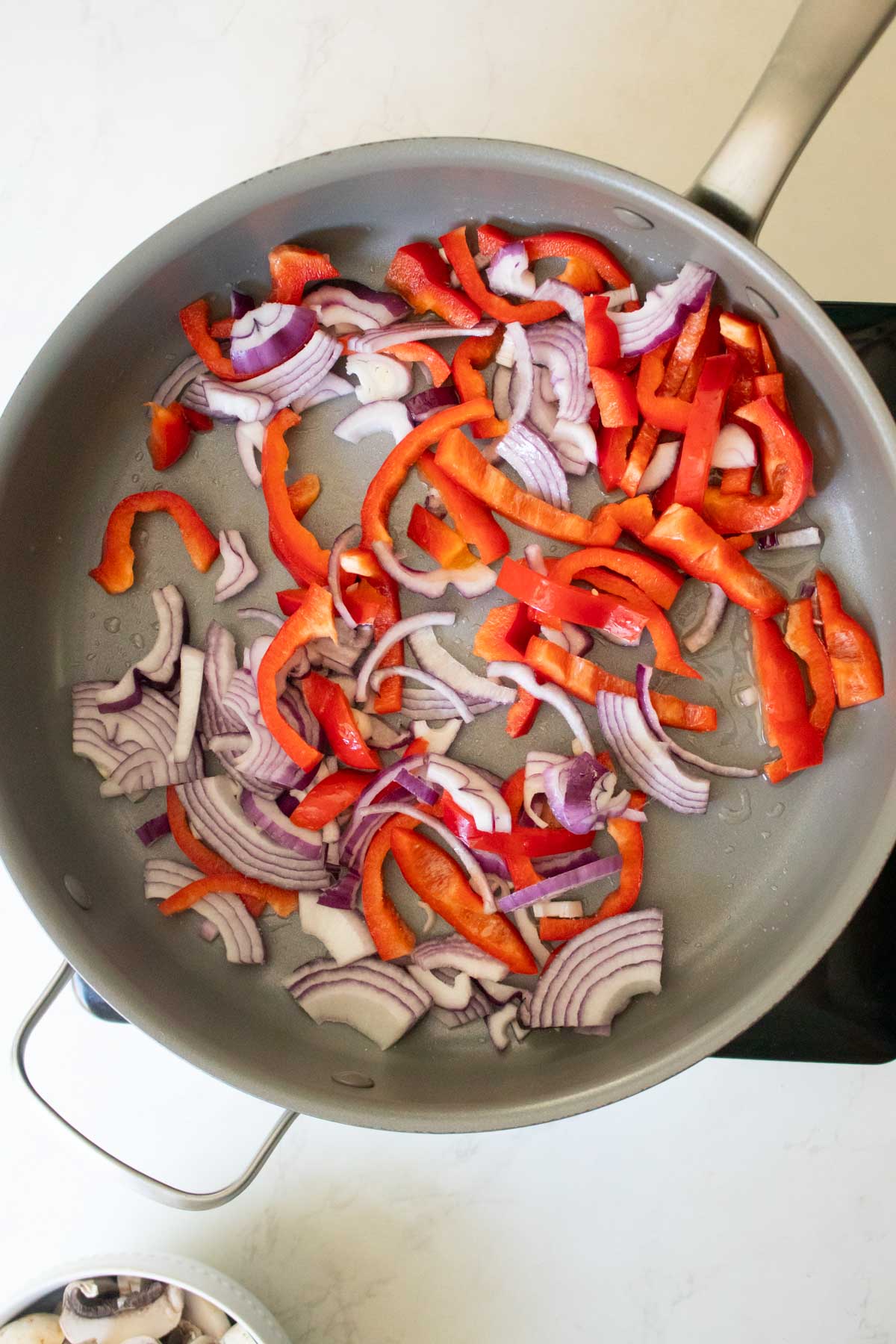 peppers and onions in the pan before cooking