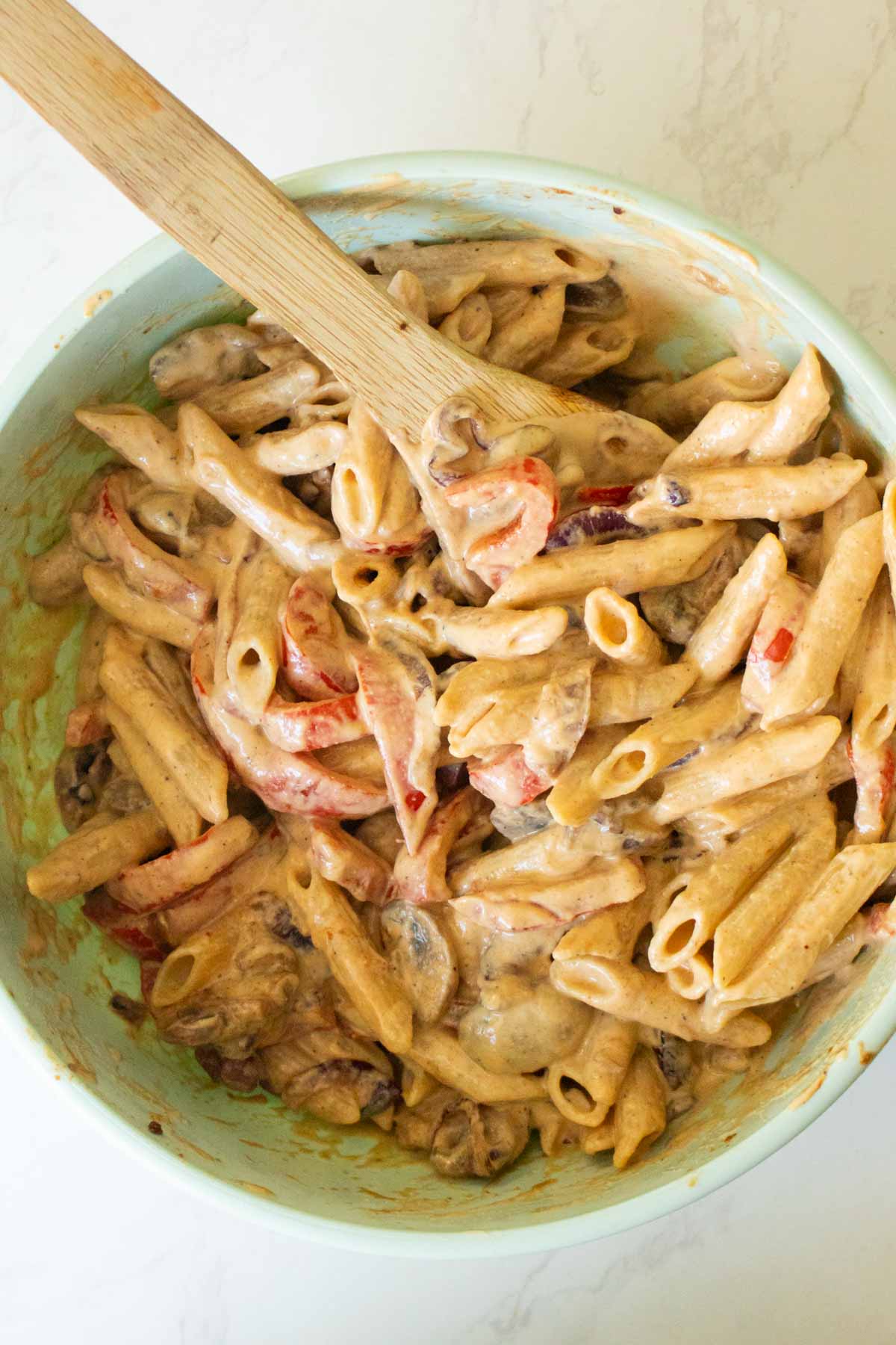 vegan Philly cheesesteak pasta in the mixing bowl after tossing it together