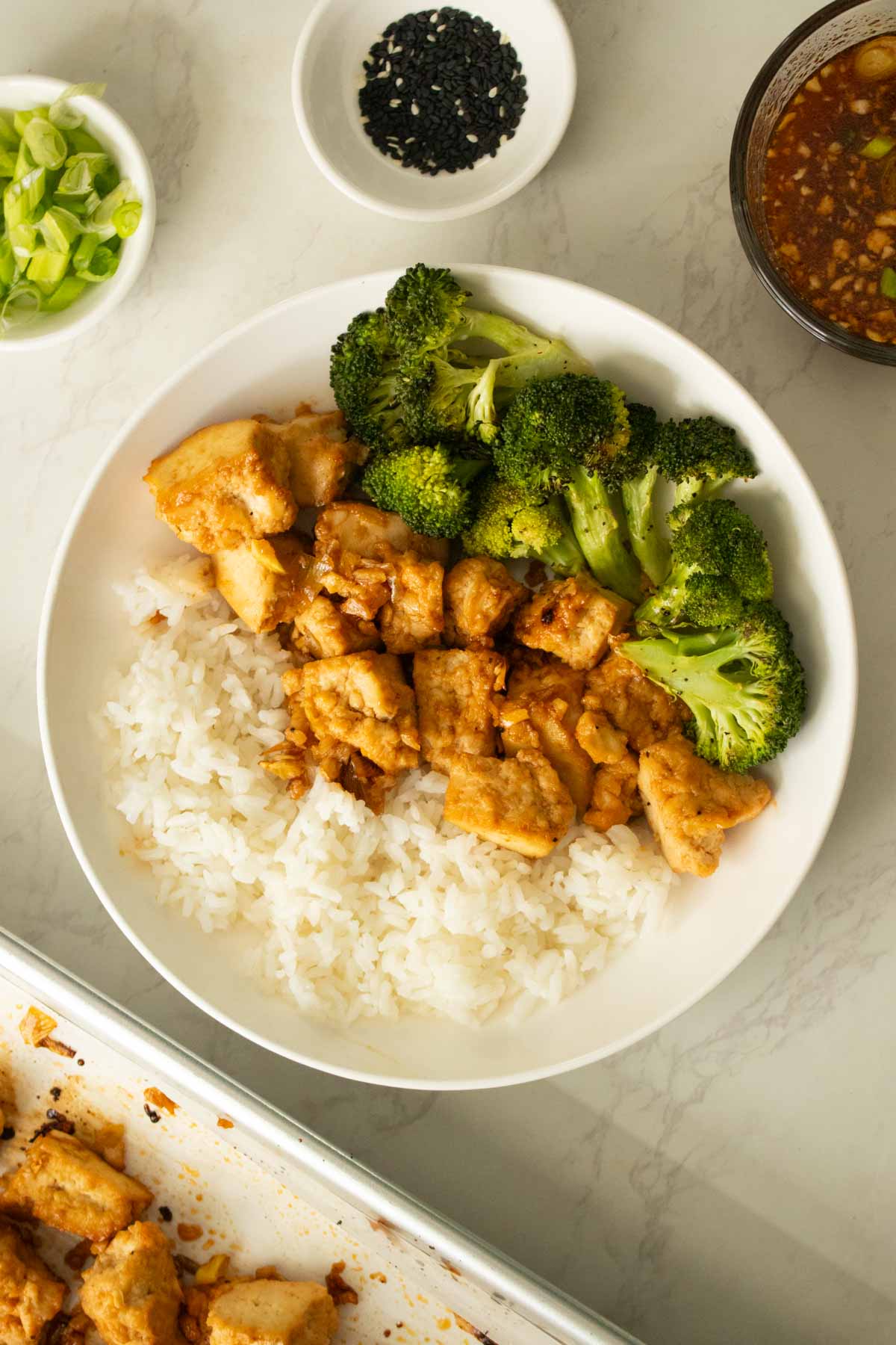 bowl of sheet pan honey garlic tofu with broccoli and rice before garnishing