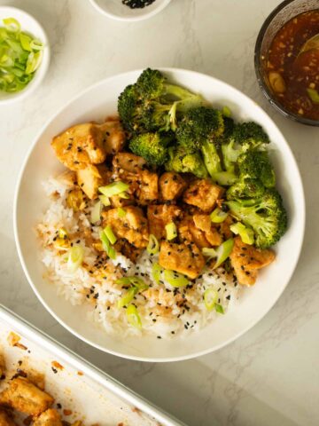 bowl of sheet pan honey garlic tofu with broccoli and rice after garnishing