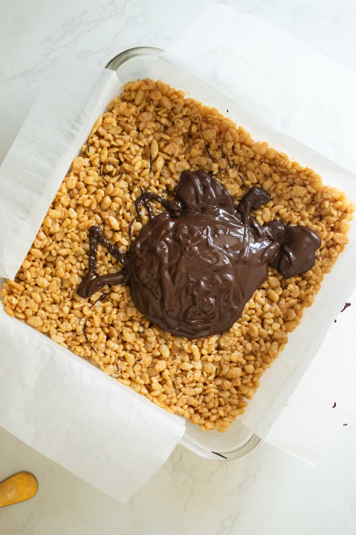 adding melted chocolate mixture to the chilled peanut butter rice crispy bars in the pan