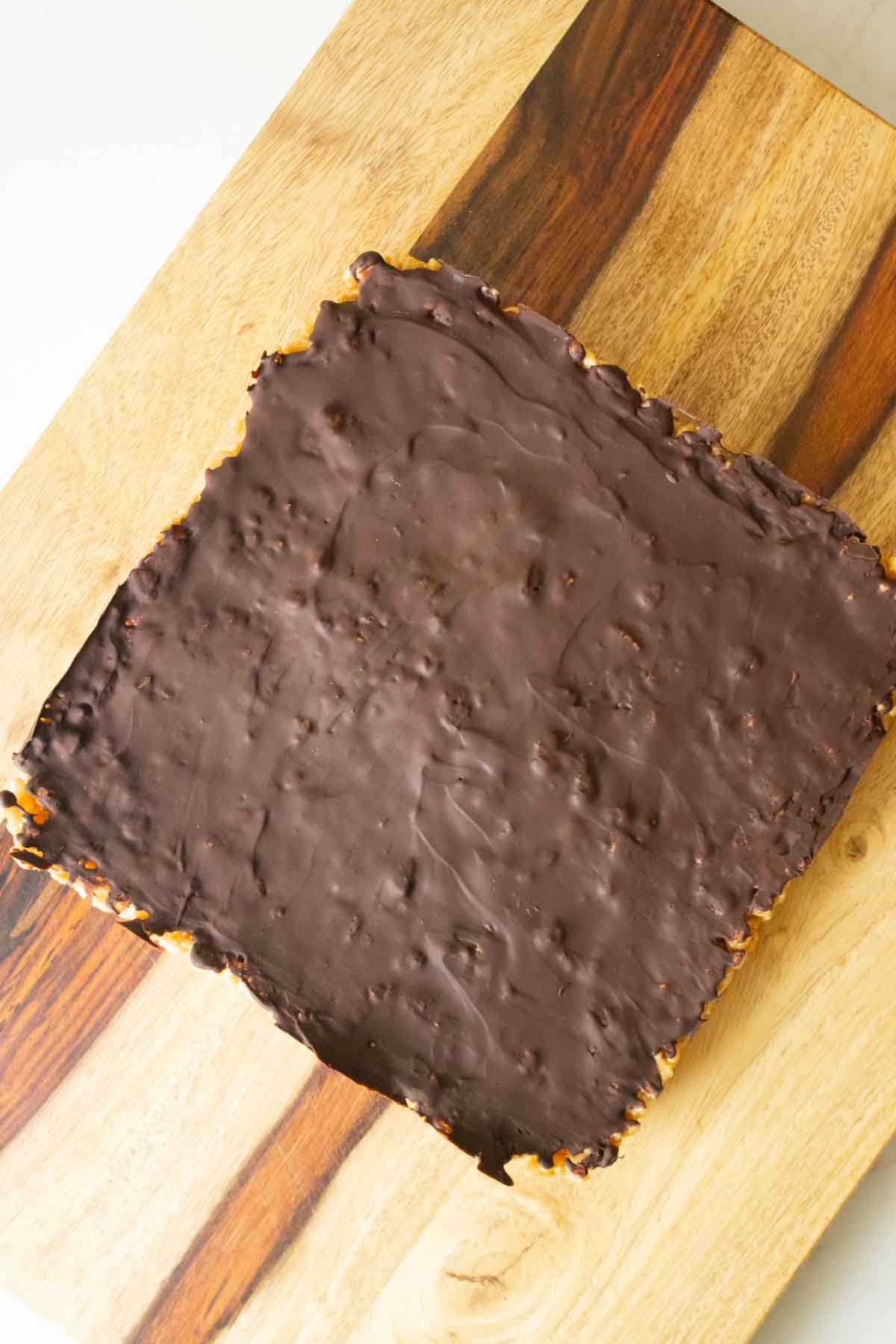chocolate peanut butter rice crispy treats on a cutting board before slicing