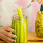 fork pulling a pickled celery spear out of a jar