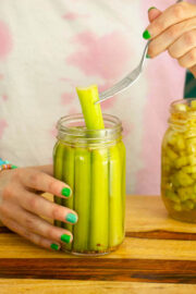fork pulling a pickled celery spear out of a jar
