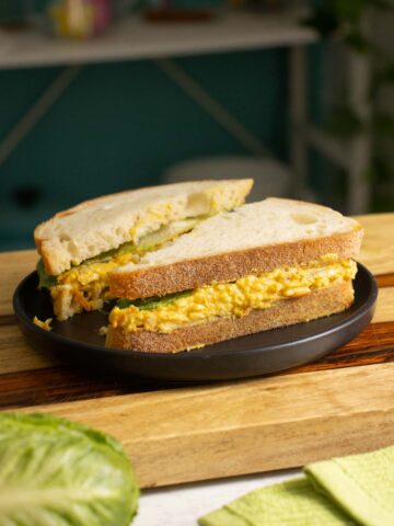 smashed white bean salad sandwich on a black plate