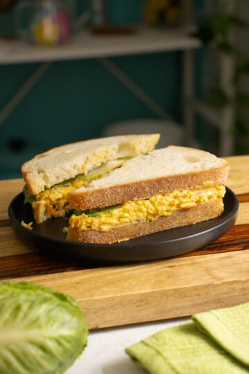 smashed white bean salad sandwich on a black plate