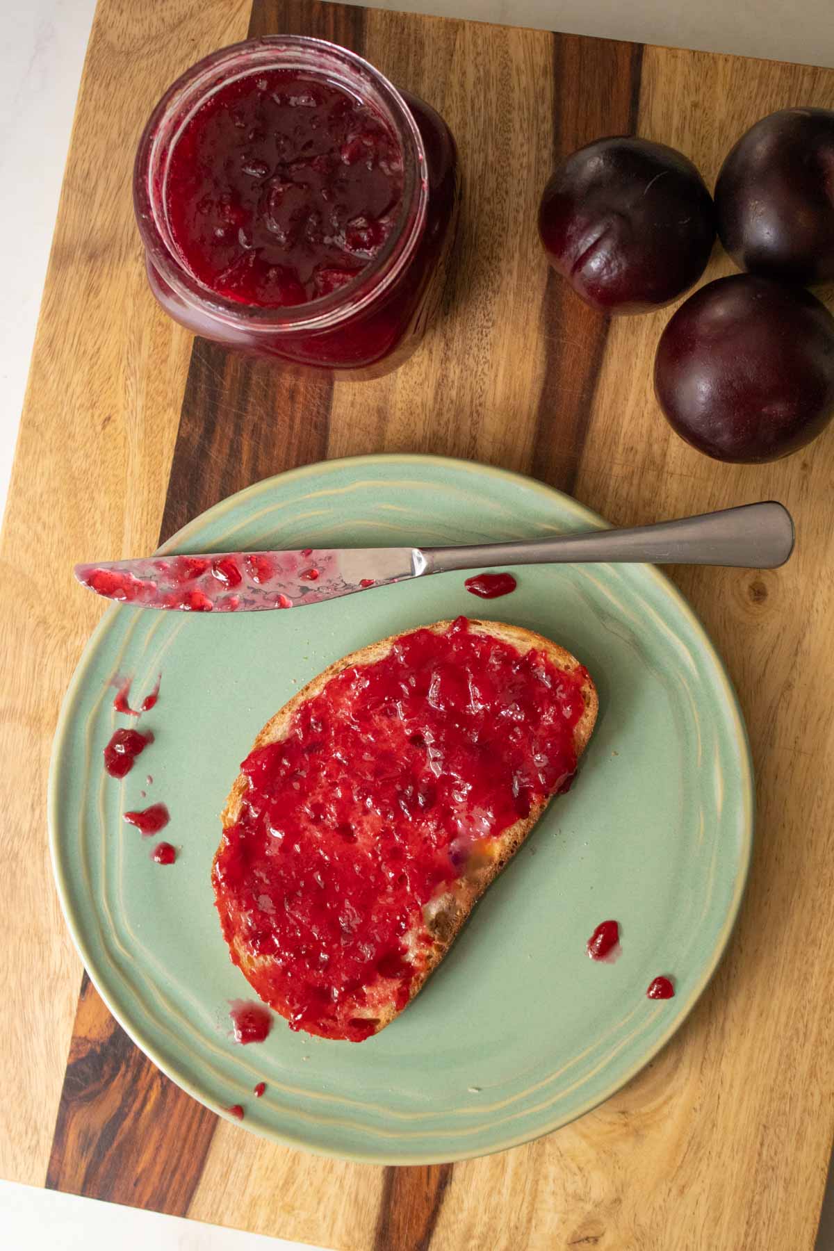 slice of toast with plum jam on a green plate