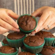 hands picking up a vegan double chocolate muffin from the serving tray