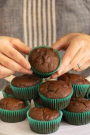 hands picking up a vegan double chocolate muffin from the serving tray