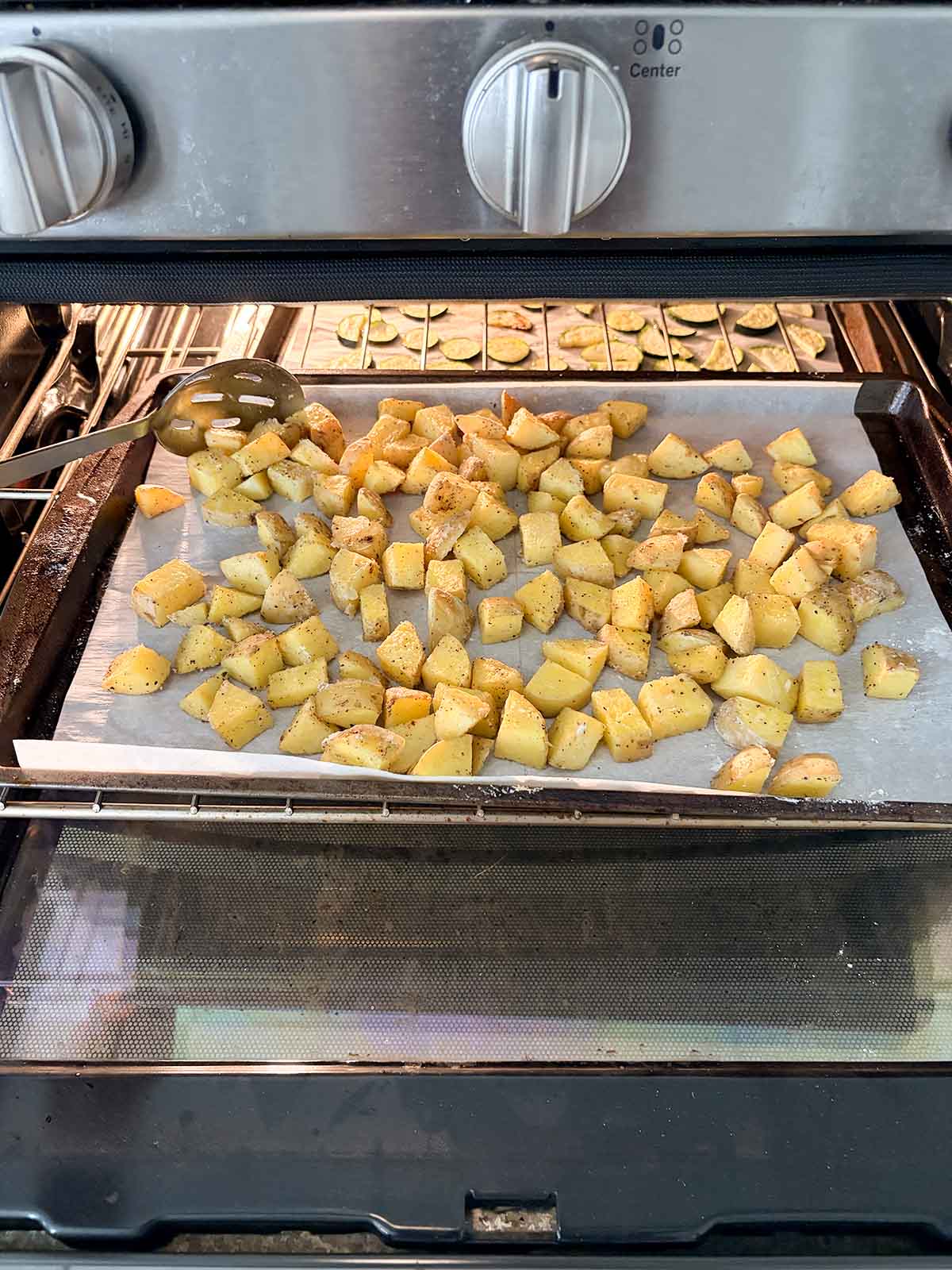 stirring the potatoes on the baking pan