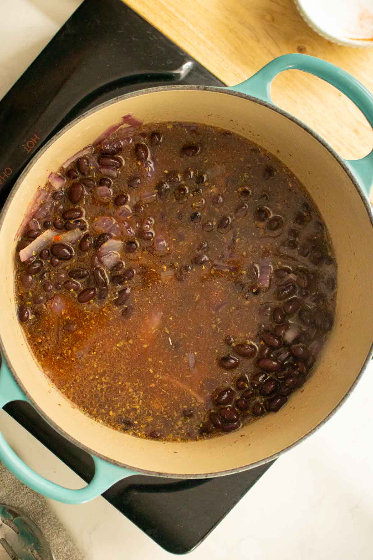 adding beans, spices, and broth to the pan