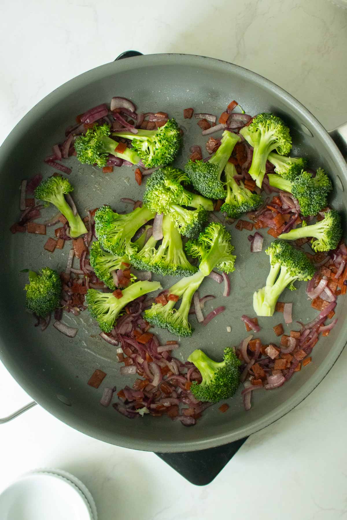 adding broccoli to the pan