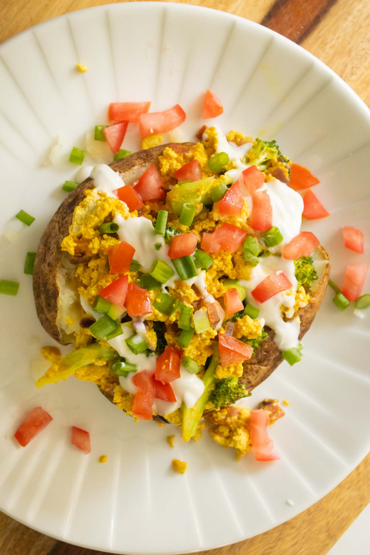 adding tomato to the breakfast loaded baked potato