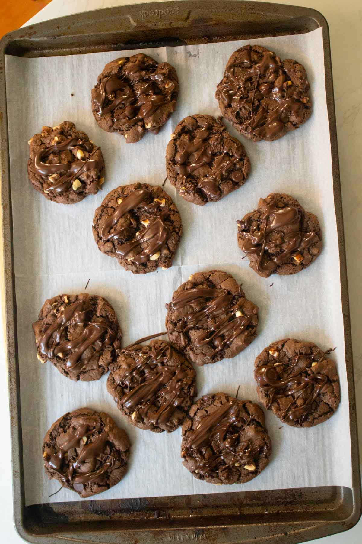 chocolate hazelnut cookies on the baking sheet after drizzling with chocolate