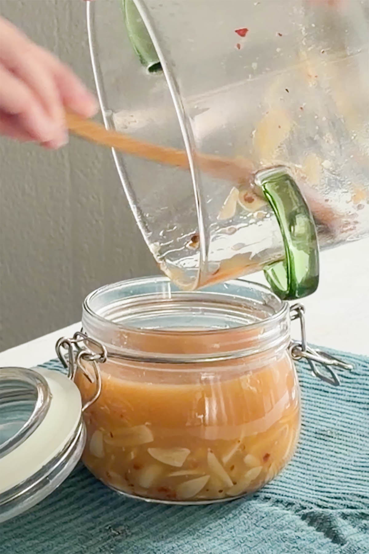 pouring the miso brine into the jar of pickled garlic