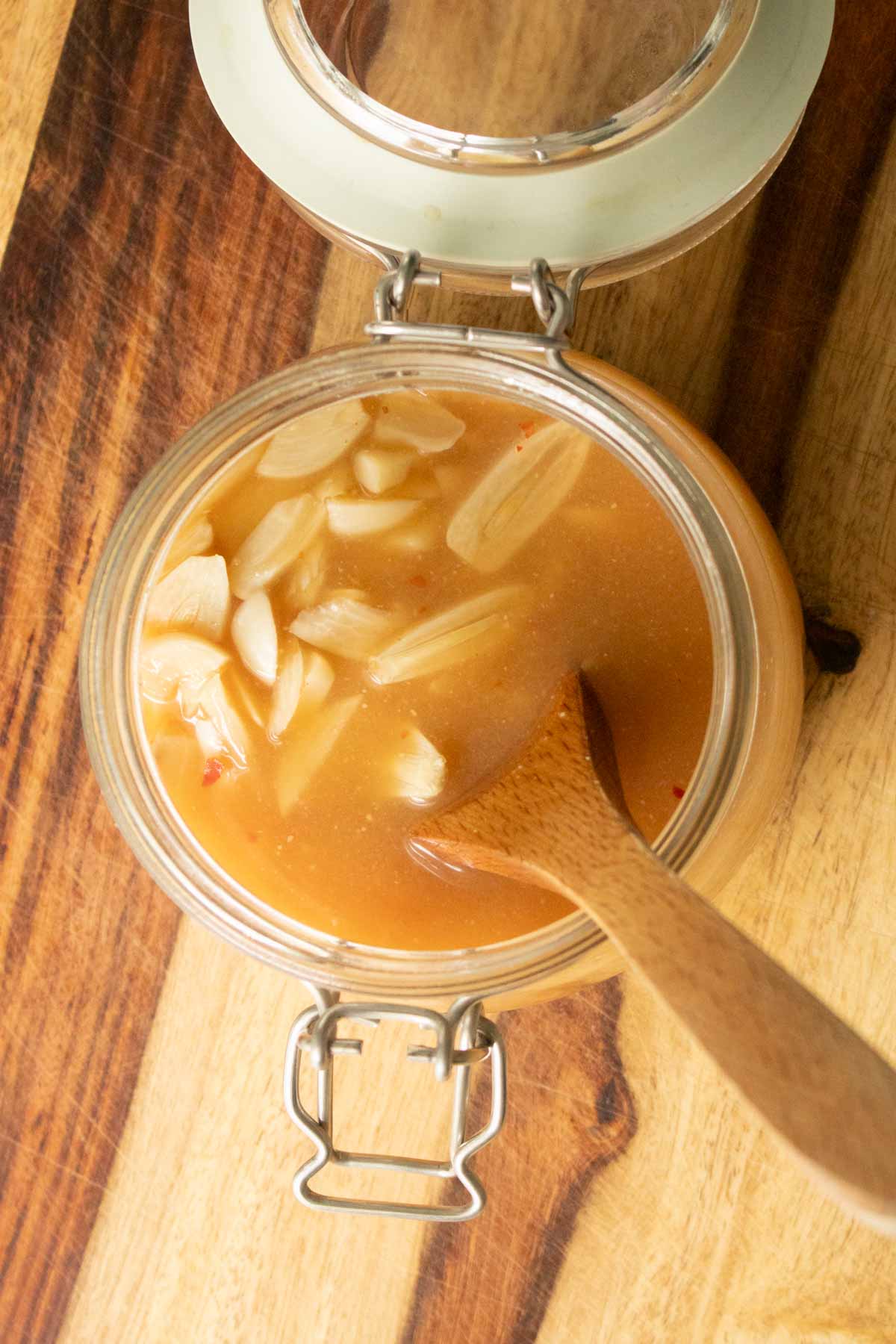 overhead shot of pickled garlic in a jar with a spoon in it