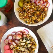 veggie rice bowls with different sauces on a wooden table surrounded by jars of sauces and pickles