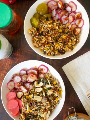 veggie rice bowls with different sauces on a wooden table surrounded by jars of sauces and pickles