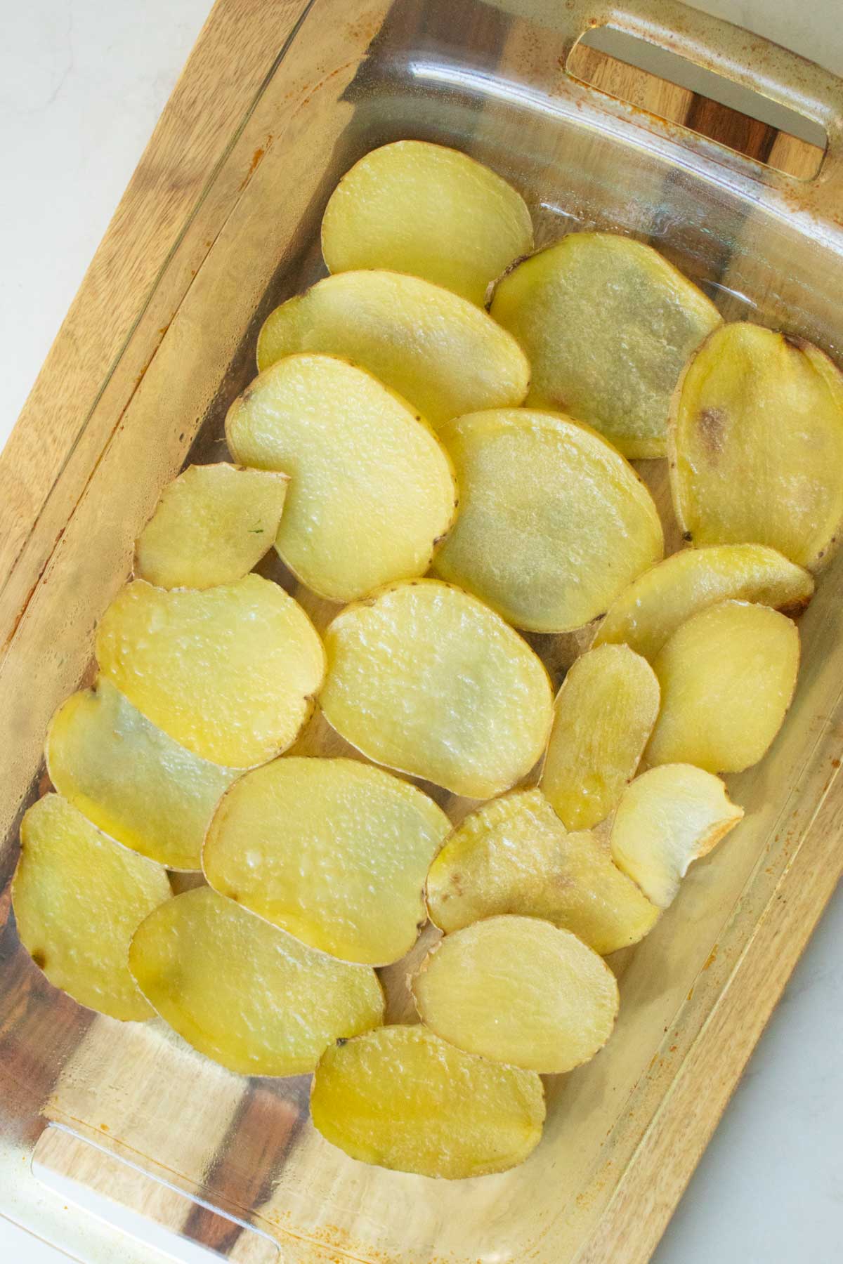 adding the potato layer to the greased baking pan