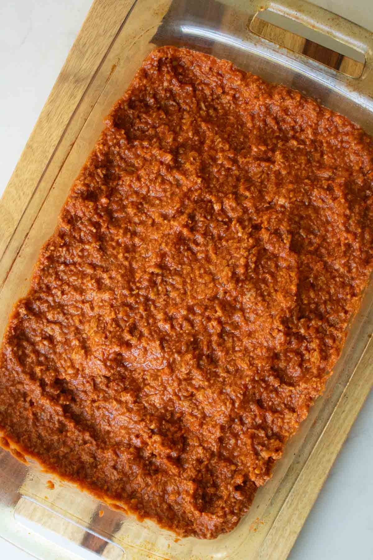 spreading the vegan meat sauce over the potato layer
