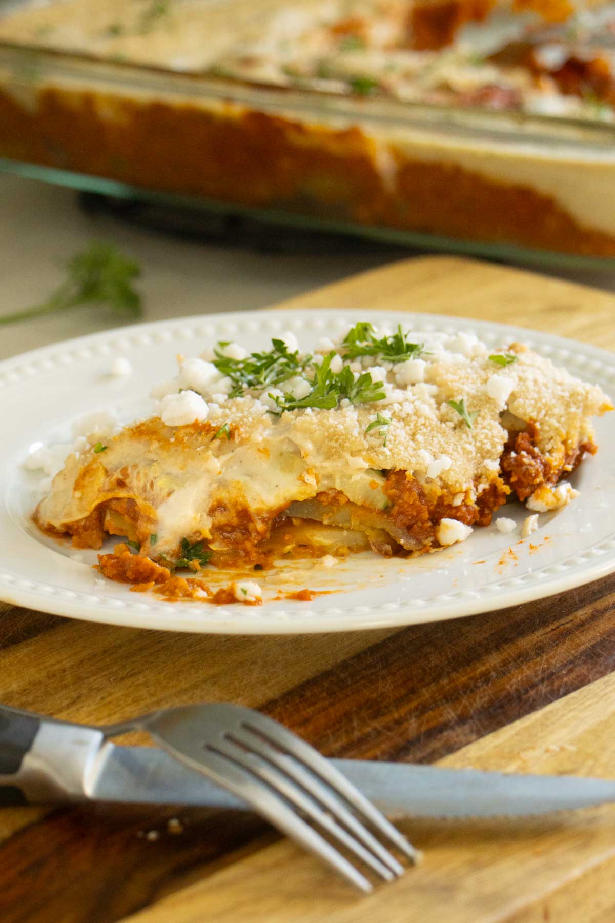 zucchini moussaka on a white plate with a bite taken out of it, so you can see the layering inside