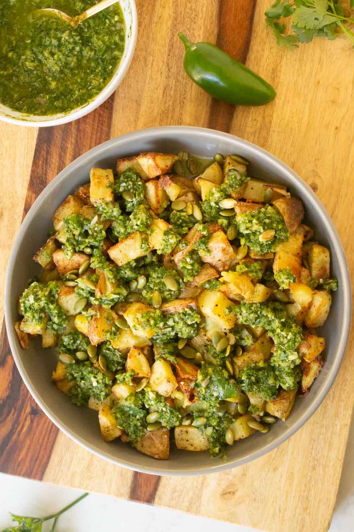 chimichurri potatoes on a serving platter next to the bowl of chimichurri