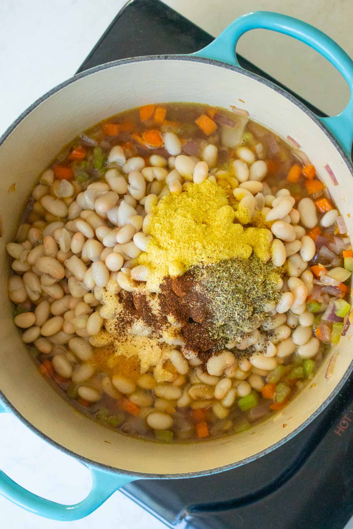 adding beans, broth, and spices to the pot