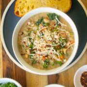 lemon white bean soup in a bowl with garnishes and a slice of bread