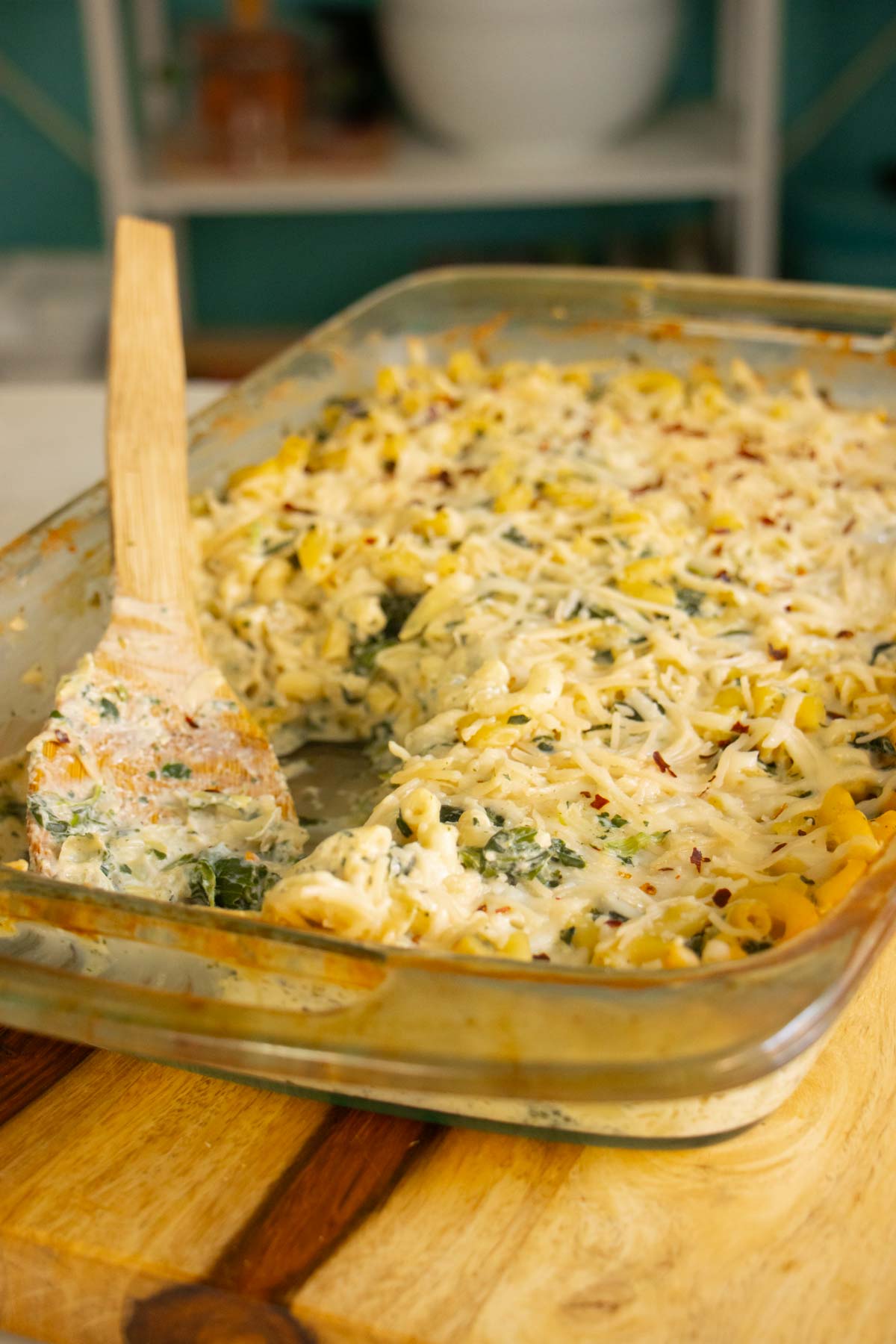 pan of spinach artichoke mac and cheese with a serving scooped out