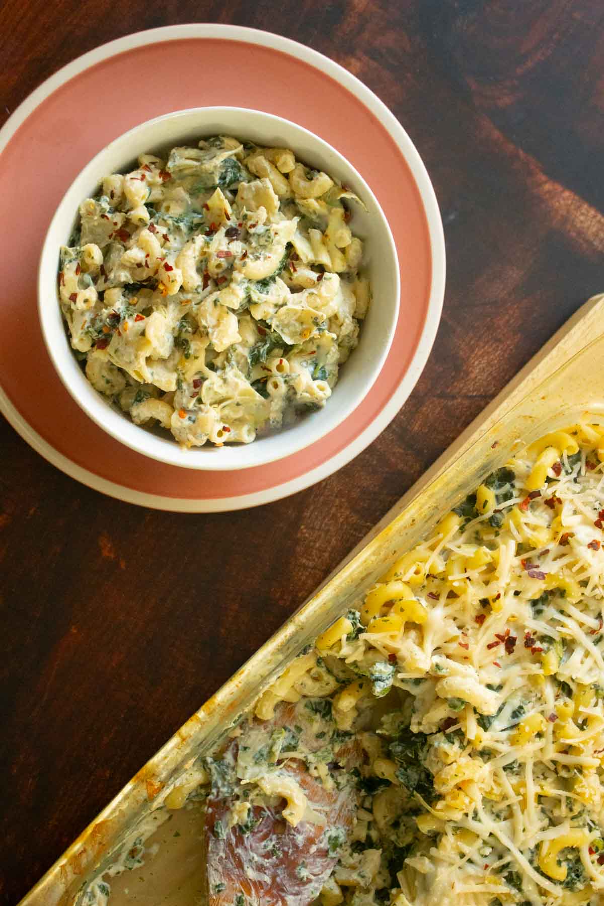 bowl of spinach artichoke mac and cheese next to the pan
