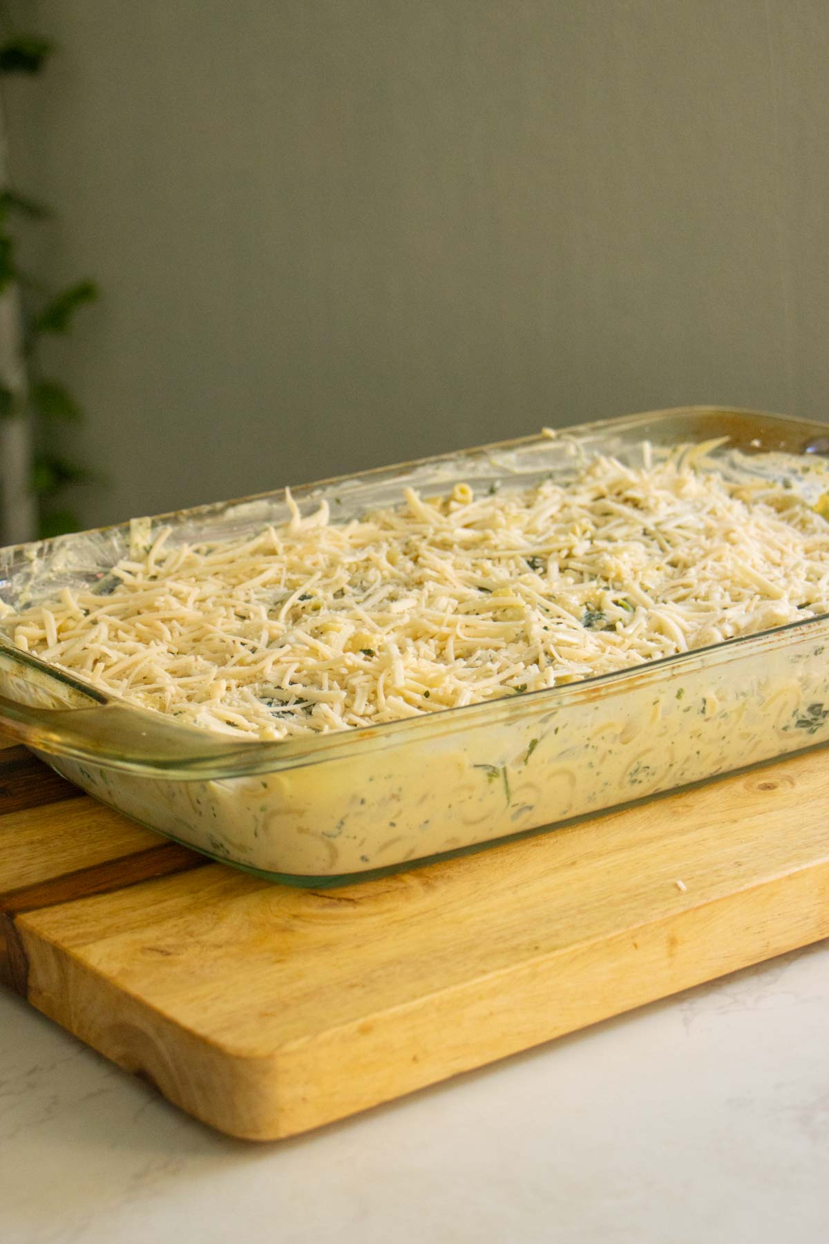 spinach artichoke mac and cheese in the pan after adding cheese topping