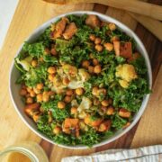 serving bowl of warm kale salad on a wooden cutting board