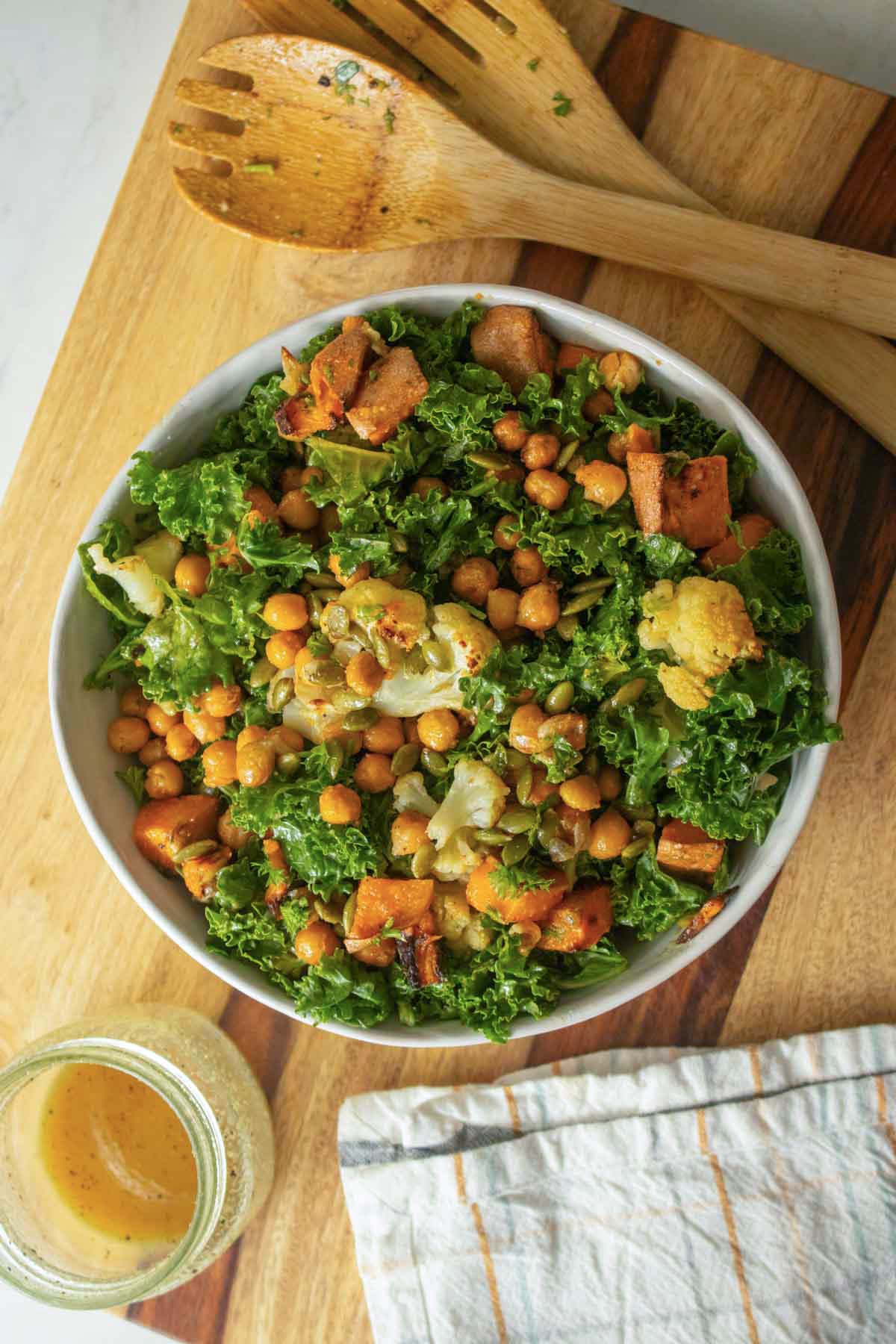 serving bowl of warm kale salad on a wooden cutting board