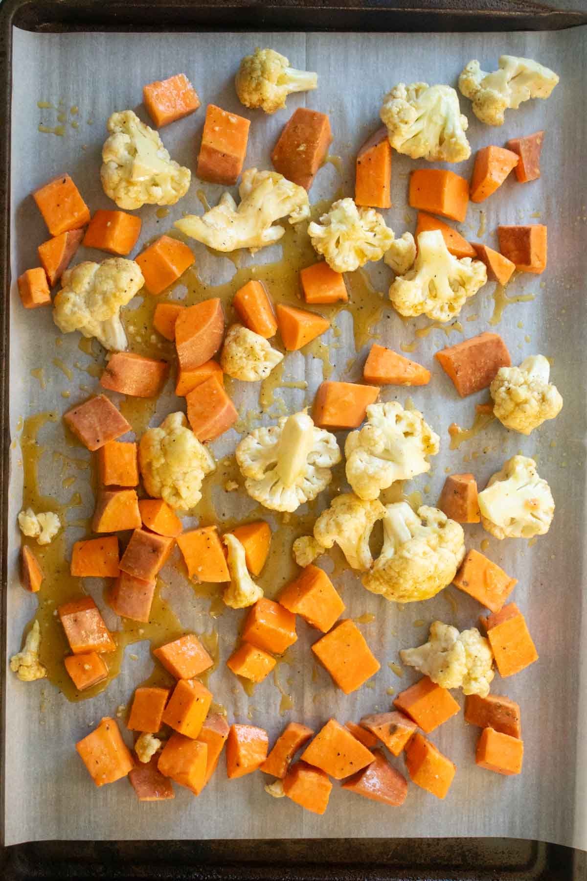 cauliflower and sweet potato on the sheet pan before baking