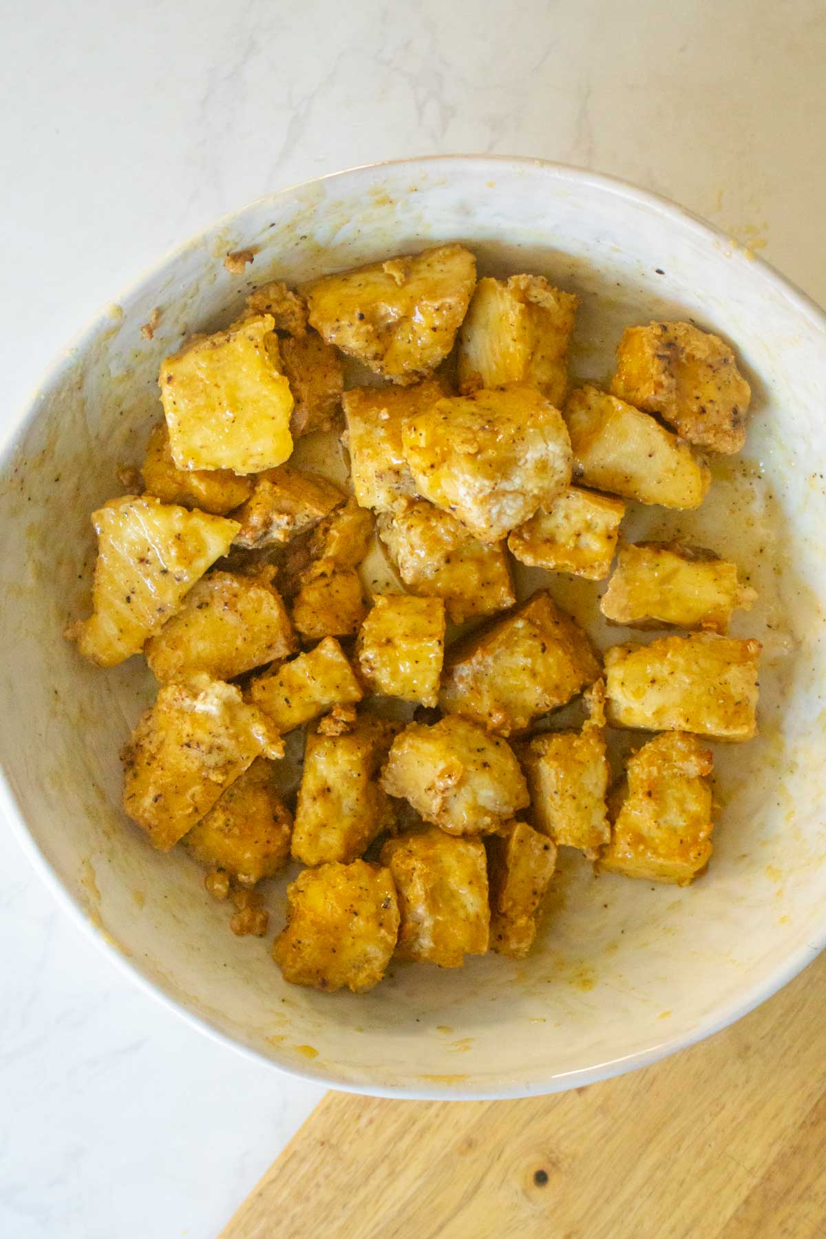 tossing the tofu with the dressing in a bowl