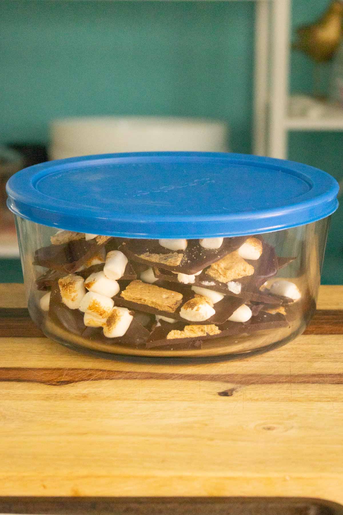 s'mores bark in a storage container with a blue lid
